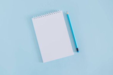 Notebook with blank page and pencil on light blue background. Flat lay. Place for text.