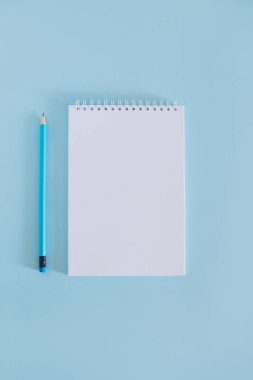 Notebook with blank page and pencil on light blue background. Flat lay. Place for text.