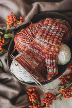 Elle örülmüş çoraplar, iğneler ve iplik yumağı. El yapımı ve yavaş yaşam için higge kavramı.