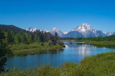 Grand Teton Ulusal Parkı 'nın sıradağları, arka planda açık gökyüzü ve ön planda ahşap çitlerle bir sabah boyunca fotoğraflanır..  