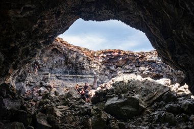 Arco, ID, USA - Jun 27, 2022: Tourists explore caves that were formed in the lava fields at Craters of the Moon National Monument & Preserve during a summer day. 