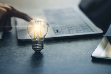 Dizüstü bilgisayarı ve kitabı olan parlak bir ampul mü yoksa kopya alanı olan bir ders kitabı mı? İş ve çevrimiçi eğitim fikri ilham ve bilgi kavramı.