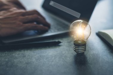 Dizüstü bilgisayarı ve kitabı olan parlak bir ampul mü yoksa kopya alanı olan bir ders kitabı mı? İş ve çevrimiçi eğitim fikri ilham ve bilgi kavramı.