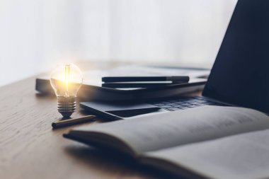 Parlak bir lamba ya da dizüstü bilgisayarlı parlak bir ampul. İş başarısı fikri ve eğitim veya çevrimiçi öğrenme kavramı. İşadamı başarısı ve ilham kaynağı.