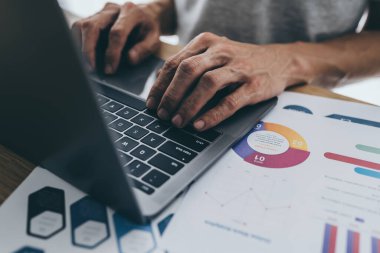 İş adamı, iş stratejisi, mali yatırım veya belge ve evrak işleriyle uğraşırken dizüstü bilgisayar kullanır veya analiz eder. Başarı pazarlama ve yönetim fikri