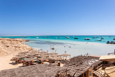 Hurghada, Mısır - 23 Eylül 2021: Orange Bay Beach kristal berrak gök mavisi suyu ve turistli tekne gemileri