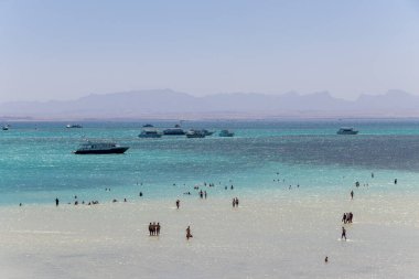 Hurghada, Mısır - 23 Eylül 2021: Orange Bay Beach kristal berrak gök mavisi suyu ve turistli tekne gemileri