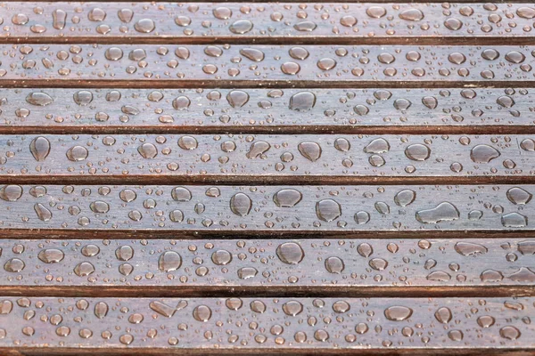 Yağmurdan sonra ahşap masaya yağmur damlaları düşer. Seçici odak