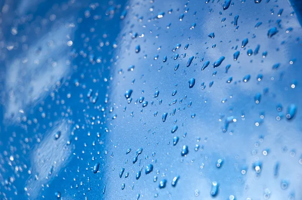 Waterdruppels op een blauwe auto — Stockfoto