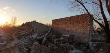 Kış günbatımının arkaplanına karşı bir tarlada tuğladan bir duvarı olan bir binanın kalıntıları.