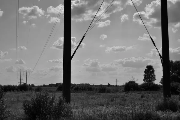 夏の空を背景にした高電圧の電柱と送電線の白黒写真 — ストック写真