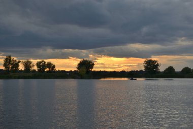 Gölün üzerinde güzel bir gün batımı. Batan güneşin ışınlarında bir balıkçı. Sonbahar manzarası.