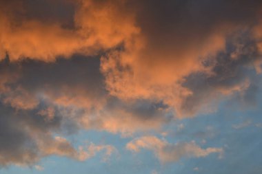 Bulutlar batan güneşin ışığında mavi gökyüzünde