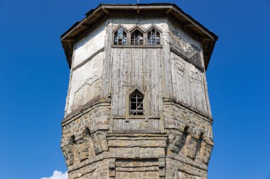 Güneşli bir yaz gününde mavi gökyüzüne bakan taş bloklardan ve ahşap panellerden yapılmış antik bir gözetleme kulesinin üst kısmı. Yakın plan.