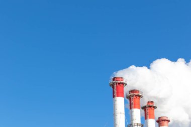 Kazan dairesinin kırmızı-beyaz bacaları, trafik ışığı ile donatılmış. Güneşli kış gününde mavi gökyüzüne karşı beyaz duman.