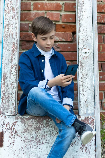 Elinde Akıllı Telefon Olan Mavi Tişörtlü Kot Pantolonlu Genç Bir — Stok fotoğraf