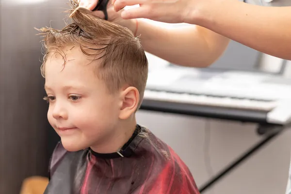 在第二次闭锁期间 一位母亲用梳子和剪刀为她的儿子理发 给她的儿子留了一个时髦的发型 选择性重点 图库图片