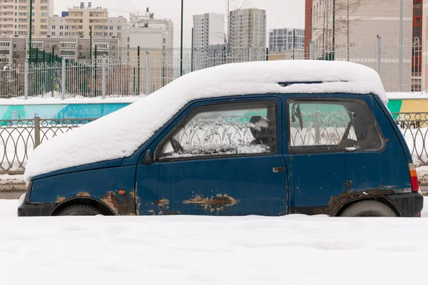 寒冷的冬日里 停在大雪下的蓝色破烂不堪的破车停在路边 免版税图库照片
