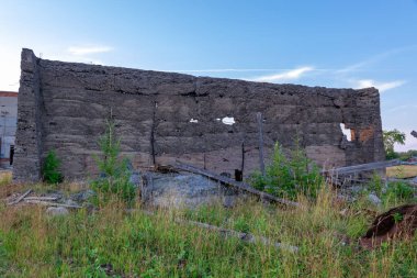 Şehrin dışındaki beton demirli beton binanın duvarını mavi gökyüzüne karşı eski gri somurtkan bir duvar yıktı. Yakın plan.