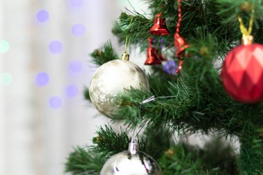 Yeşil dalları olan yeni yıl ağacı ve yılbaşı arifesinde çelenklerin arka planında Noel süslemeleri olan iğneler. Seçici odaklanma. Yakın plan.