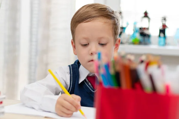 一个穿着校服的可爱的一年级男孩坐在办公桌前 手里拿着铅笔 一边做作业 远程教育 有选择的重点 肖像画 — 图库照片