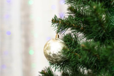 Yeşil dalları olan yeni yıl ağacı ve yılbaşı arifesinde çelenklerin arka planında Noel süslemeleri olan iğneler. Seçici odaklanma. Yakın plan.