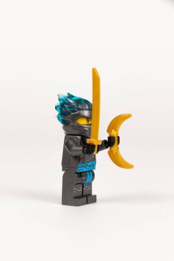 Yekaterinburg 'da. - Rusya. 04.08.2021. Oyuncak kahraman Nya, gri kimonolu, oraklı ve beyaz arka planda bir lego ninjasının kılıcıyla. Yakın plan. seçici odak