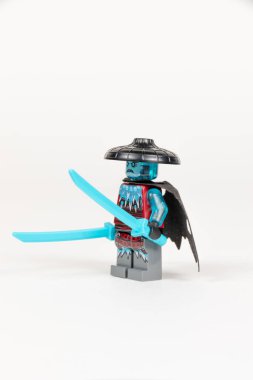 Yekaterinburg 'da. - Rusya. 04.08.2021. Oyuncak kahraman Kar Fırtınası Kılıç Ustası pelerinli iki buz kılıcı ve beyaz arka planda bir lego ninjasından alınmış bir şapkayla. Yakın plan. seçici odak