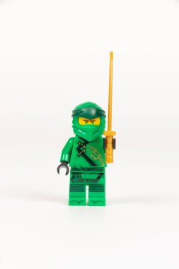 Yekaterinburg 'da. - Rusya. 04.08.2021. Oyuncak kahraman Lloyd yeşil kimonolu ve beyaz arka planda Lego ninjalarının kılıcıyla. Yakın plan. seçici odak