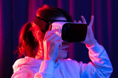 Sanal gerçeklik gözlüklü genç bir kadın ve mavi menekşe arka planda beyaz kapüşonlu bir kazak. Modern teknolojiler. Seçici odaklanma. Portre