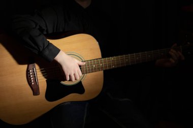 Metal telli akustik gitar çalan bir müzisyenin elleri. Hobi olarak. Müzik aletleri. Seçici odaklanma. Yakın plan.