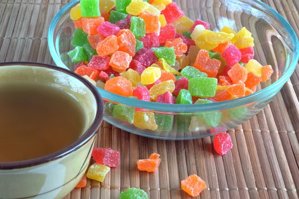 Piala con tè e un piatto di vetro con frutta candita — Foto Stock