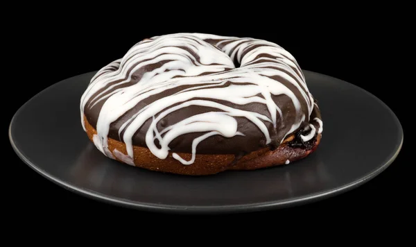 Broodje bedekt met chocolade, in een donkere plaat op een zwarte achtergrond — Stockfoto