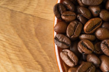 Kahve taneleri bir fincanda, tahtaya yakın çekim.