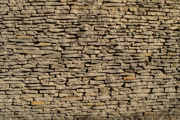 Açık renkli kumtaşı duvar. Taşın dokusu yakın..