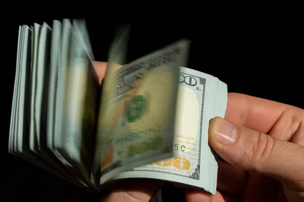 A man\'s hand counts paper dollar bills close up.