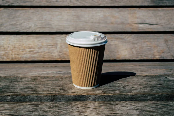 Disposable coffee cup on a wooden surface close up.