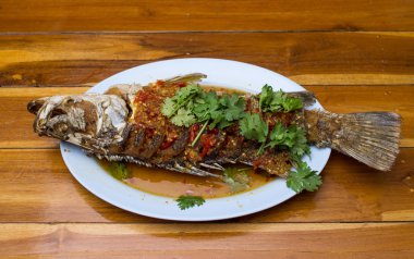 ahşap masa ile plaka chili soslu kızarmış snapper