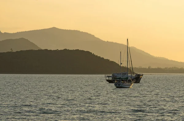Два туристичні човни на морі з гірським тлом, коли сходить сонце — стокове фото