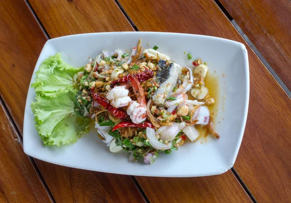 Пряный салат из морепродуктов в тарелке на деревянном столе — стоковое фото