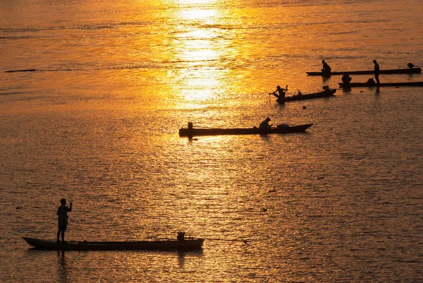 Muchos Pescador remando un bote de remos para la pesca al atardecer, Silh — Foto de Stock