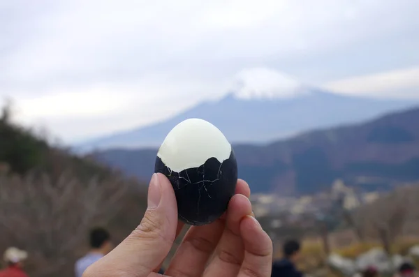 Hold black boiled egg with Fuji mountain background, Fuji Hakone — Stock Photo, Image