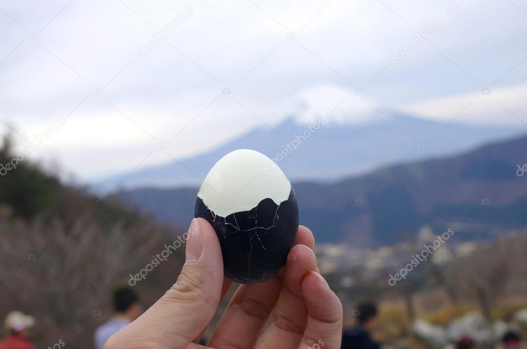 hold black boiled egg with Fuji mountain background, Fuji Hakone