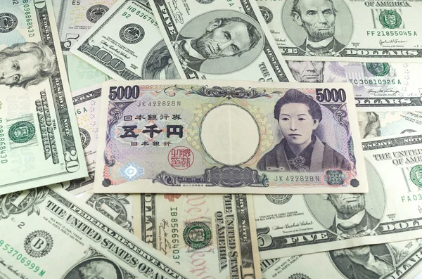 Five thousand Japanese yen notes on many dollars background — Stock Photo, Image