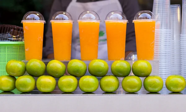 Апельсиновый смузи и фрукты на столе для продажи — стоковое фото