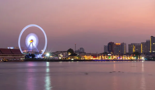 Ferris lado del río rueda en la hora del crepúsculo en Bangkok paisaje urbano — Foto de Stock