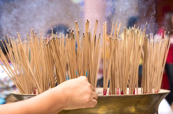 Hand places a stick of incense at a large pot in Chinese temple — Stock Photo, Image