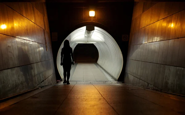 Silhueta de mulher indefinida caminhando na passarela subterrânea — Fotografia de Stock