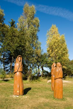 ahşap heykeller önünde ağaçlar çayırda