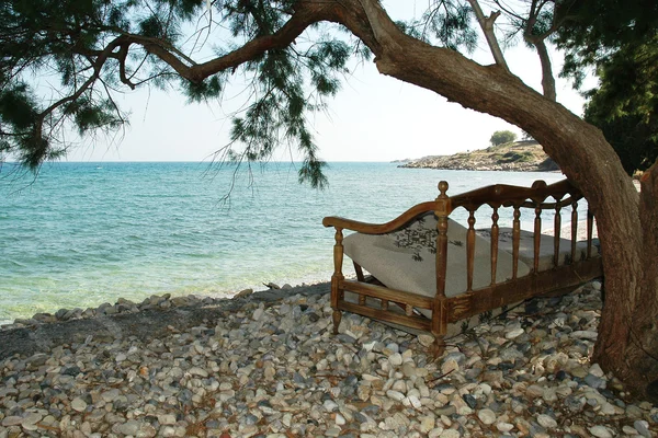 Cadeira velha para descansar debaixo de uma árvore junto ao mar — Fotografia de Stock